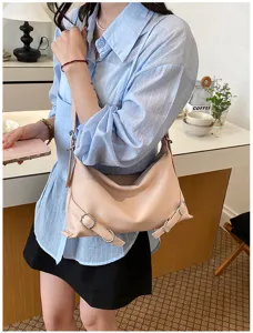 Gros plan de détail élégant sac porté épaule en cuir rose avec boucles métalliques.
