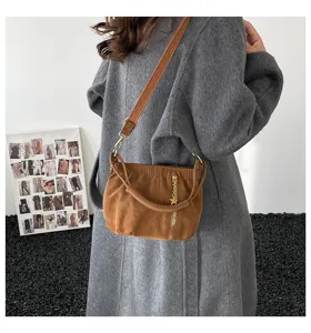 Brown suede shoulder bag detail showing ruched design, gold zipper, and star charm pendant.