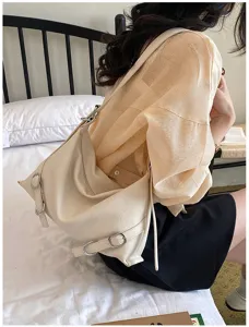 Vue détaillée du sac porté épaule crème avec boucles métalliques chics et cuir souple.