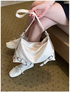 Détail de sac à bandoulière sous les bras en cuir blanc montrant texture douce et accessoires métal.