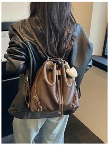 Mochila de cuero marrón con cierre de cordón y bonito colgante de oso de peluche.
