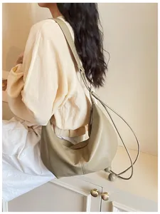 Detail view of stylish minimalist hobo shoulder bag, soft leather with trendy knot strap.