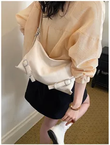 Vue de détail d'un sac sous les bras élégant en cuir blanc cassé avec boucles en métal.