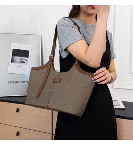 Detail view of the brown canvas tote bag, showcasing dual shoulder straps and fine stitching.