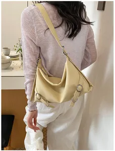 Gros plan sur le sac besace jaune beurre élégant avec des boucles sur les côtés.