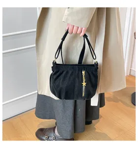 Detail shot showing the black suede handbag with gold zipper and star charm, versatile style.
