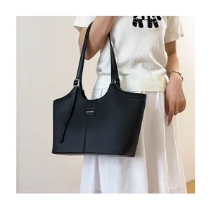 Detailed view of black leather tote bag with shoulder straps and fashion logo accent.