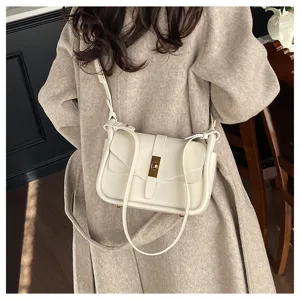 Detail view of creamy white leather messenger bag, adjustable strap and metal turn-lock.
