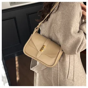 Detailed shot of retro beige crossbody bag with metal lock and soft leather texture design.