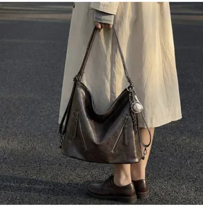 Detailed shot of retro brown hobo tote bag with dual front zippers and baseball charm outdoor.