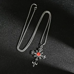 Macro view of a gothic silver cross pendant with a brilliant red gemstone detail