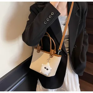 Chic woven bucket bag with brown handles and cute plush charm for women summer style.