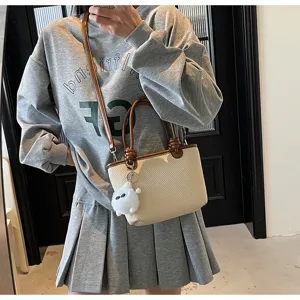 Woven bucket bag for women, chic straw shoulder bag with top handles and cute fluffy charm.