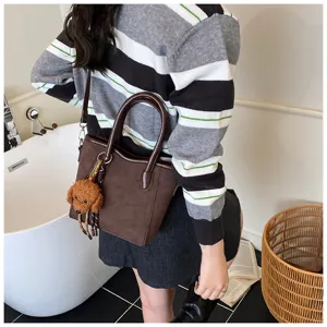 Detailansicht der koreanischen braunen Handtasche mit süßem Plüschtieranhänger für Damen.