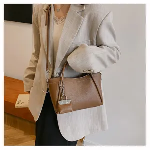 Detailed view of brown leather handbag, stylish commuter shoulder bag with chain charm.