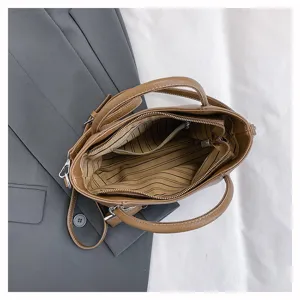 Handbag interior detail showcasing large capacity, striped inner lining, and secure zipper pockets.