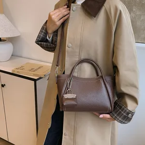 Stylish brown leather handbag for women, elegant casual commuter crossbody tote bag with top handle.