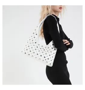 Detailed shot of white studded shoulder bag with metallic silver dots worn by model.