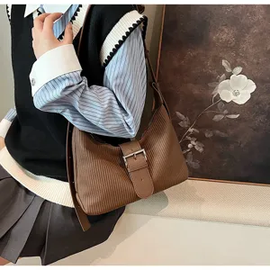 Vintage brown textured shoulder bag detail, elegant buckle strap and commuter crossbody style.