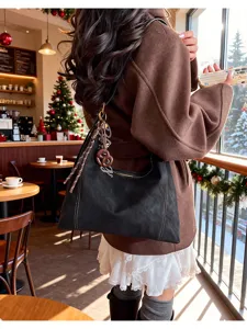 Detail shot of stylish black hobo shoulder bag featuring unique charms and retro design.