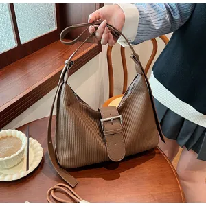 Detail view of vintage retro striped shoulder bag with stylish metal buckle in cozy setting.