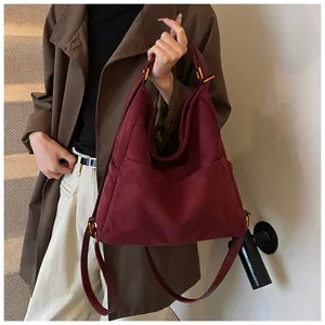Vista dettagliata della grande borsa a tracolla e zaino retrò in camoscio bordeaux da donna.