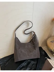 Detailed shot of a vintage style grey hobo shoulder bag with soft suede texture and charms.
