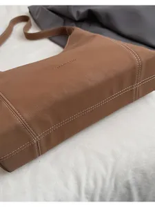 Brown PU leather shoulder bag detail showing contrast white stitching and hobo tote shape.