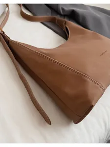 Detailed view of brown vintage leather shoulder bag with contrast stitching and sleek hobo shape.