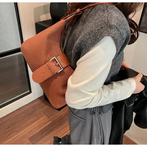Detailed view of brown striped textured underarm shoulder bag with metal belt buckle detail.