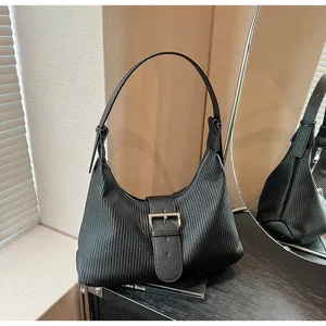 Detail view of a stylish black textured shoulder bag with a front buckle and single strap.