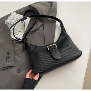 Detailed view of the black textured shoulder bag featuring an elegant metal buckle design.