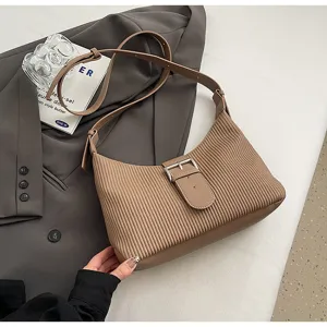 Detailed view of brown pleated shoulder bag with stylish belt buckle and retro design.