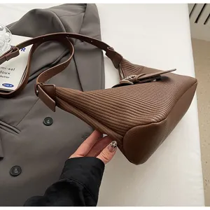 Close-up detail of the brown embossed shoulder bag showcasing textured leather and buckle design.