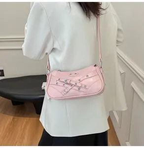 Close-up view of pink leather motorcycle shoulder bag showcasing trendy buckled strap details.