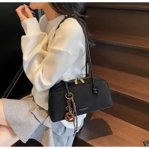 Detail shot of a black matte shoulder bag styled on a wooden staircase with a stylish pendant.