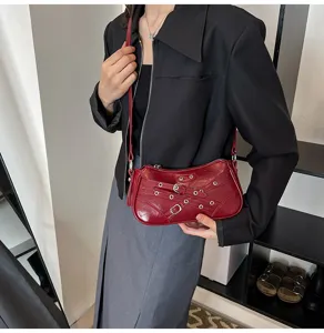 Red motorcycle style shoulder bag with metal buckle detail shown in close up view.