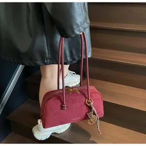 Detailed view of the dark red vintage suede shoulder bag showcasing long double straps and charms.