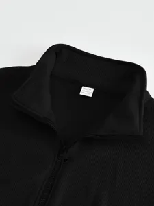 Close-up detail of black ribbed stand-collar jacket, half-zip design, soft texture fabric.