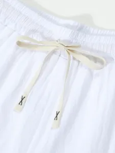 Close-up detail of white casual shorts waistband with drawstring and black embroidery X accents.