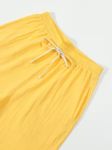 Close-up detail of yellow casual pants waistband with adjustable white drawstring design.