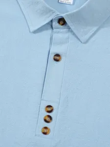 Close-up detail view of light blue cotton linen mens long sleeve shirt collar and buttons.