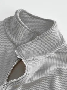 Close-up detail of mens grey ribbed stand collar zip-up jacket fabric texture.