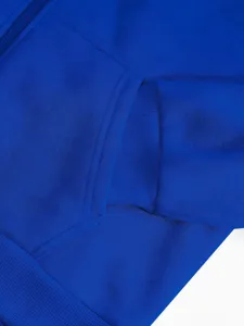 Close-up detail of royal blue hoodie zipper pocket and ribbed cuff texture, minimalist shot.