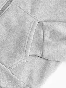 Grey zip-up hoodie detail showcasing the pocket and ribbed cuff texture, comfortable fabric.