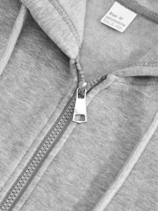 Close-up detail of casual men's grey hooded sweatshirt zipper and polyester care label.