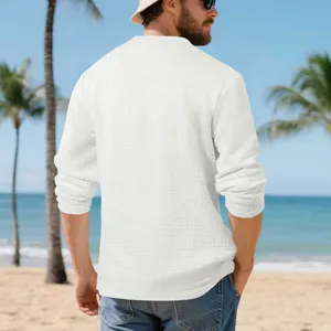 Detailed back view of men's white textured waffle grid long sleeve shirt on beach scene.