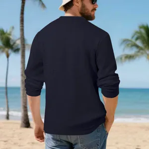 Detail view of men's textured long sleeve t-shirt with waffle jacquard pattern on beach background.