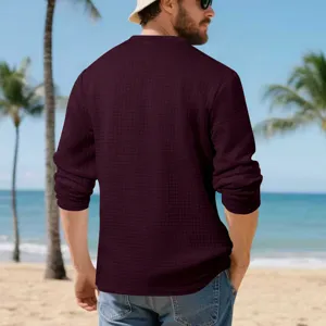 Detail shot of men's long sleeve jacquard grid henley shirt in deep red worn on beach.
