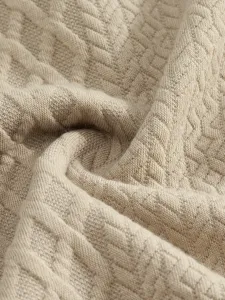 Close-up detail of mens casual suit fabric, showing soft beige jacquard texture and knit drape.